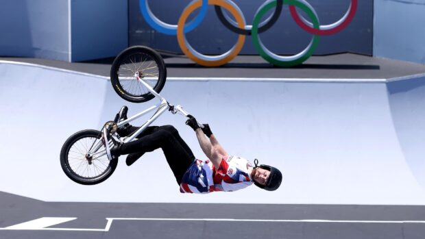 A BMX sports athlete performs a trick in front of Olympic rings, 2K Desktop Wallpaper