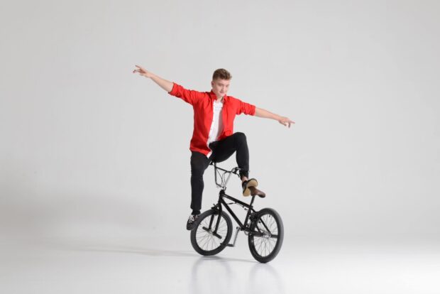 A young man in a red shirt performing a BMX sports stunt on a black bike, 2K Desktop Wallpaper