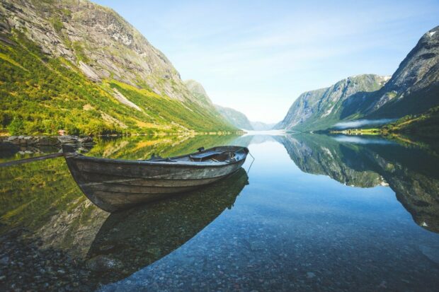 A boat floats on a calm lake surrounded by green mountains and clear skies in Norway Wallpapers, HD Desktop Wallpaper