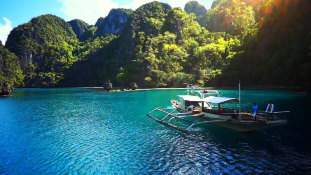 A boat sails near lush green islands and clear blue water in Palawan, HD Desktop Wallpaper