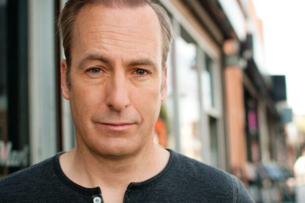 Bob Odenkirk stands in an urban setting with a focused expression, 2K Desktop Wallpaper