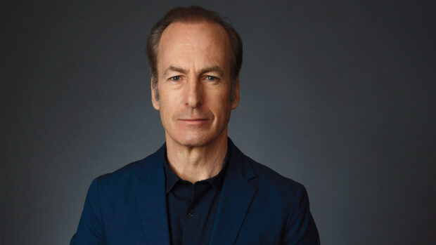 Bob Odenkirk is wearing a dark blue suit and looking straight ahead against a grey background, HD Desktop Wallpaper