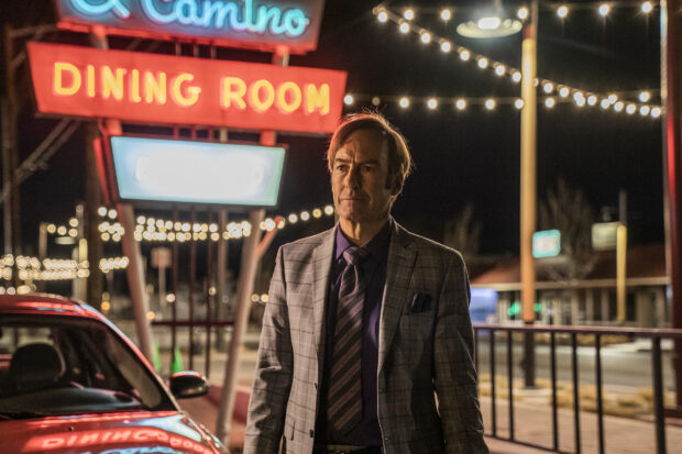 Bob Odenkirk stands near a neon dining room sign at night with lights in the background, HD Desktop Wallpaper