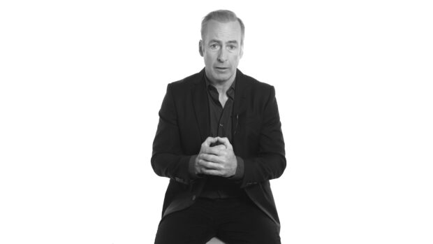 Bob Odenkirk is sitting and speaking in a black suit, HD Desktop Wallpaper