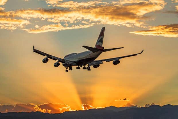 A Boeing 747 approaching for landing with a vibrant sunset and mountain silhouette, HD Desktop Wallpaper