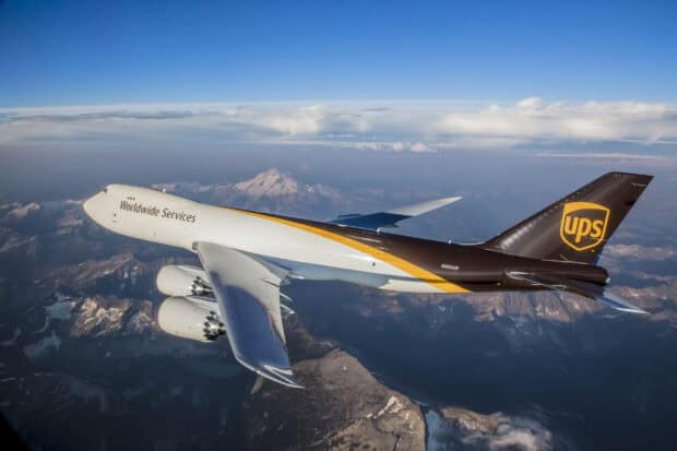 A Boeing 747 cargo plane with UPS livery flying above mountains and clouds, 2K Desktop Wallpaper