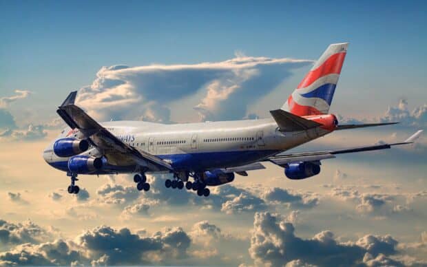 A Boeing 747 aircraft is flying over a cloudy sky during sunset, 2K Desktop Wallpaper