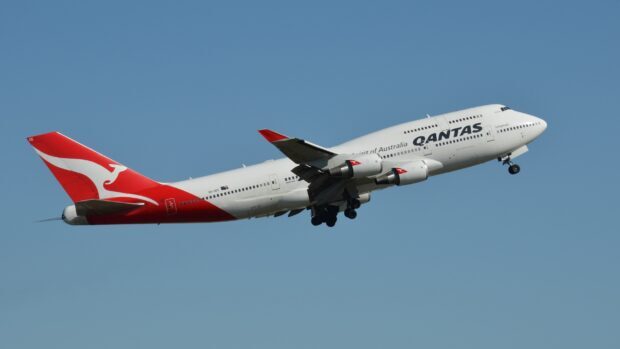 A Boeing 747 aircraft with Qantas colors takes off under clear blue sky, 2K Desktop Wallpaper