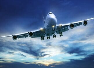 A Boeing 747 jet is captured flying low with landing gear down during a vibrant sunset, 2K Desktop Wallpaper