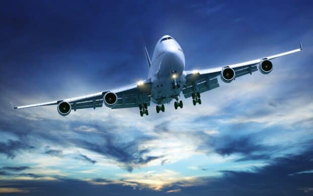 A Boeing 747 jet is captured flying low with landing gear down during a vibrant sunset, 2K Desktop Wallpaper