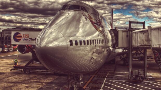 A Boeing 747 is connected to the airport jet bridge on a cloudy day, HD Desktop Wallpaper