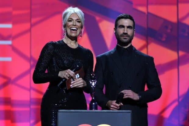 Brett Goldstein stands next to a woman on stage holding a microphone with an award in front of them, 2K Desktop Wallpaper