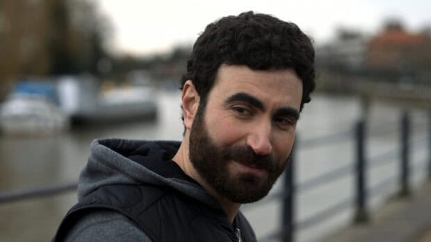 Brett Goldstein portraits while standing near a river and railing, HD Desktop Wallpaper