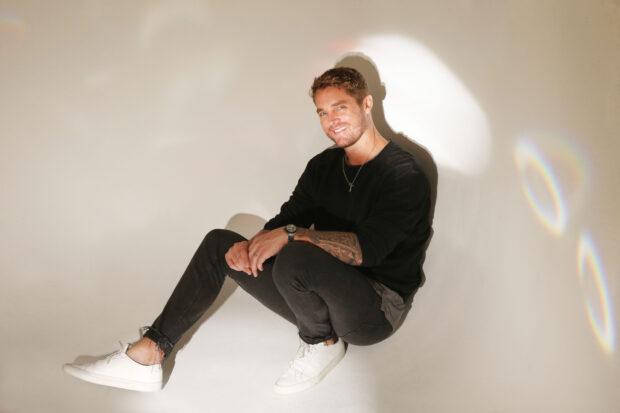 A man with tattoos and casual clothes sits smiling in bright light with Brett Young wallpapers, 2K Desktop Wallpaper