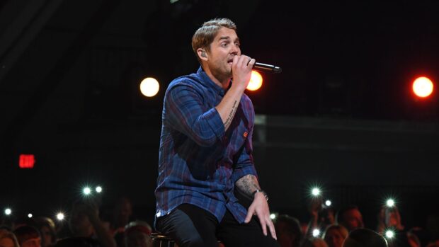 Brett Young is singing into a microphone during a live concert, HD Desktop Wallpaper