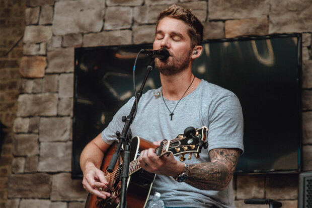 Brett Young is singing and playing guitar during a live performance, HD Desktop Wallpaper