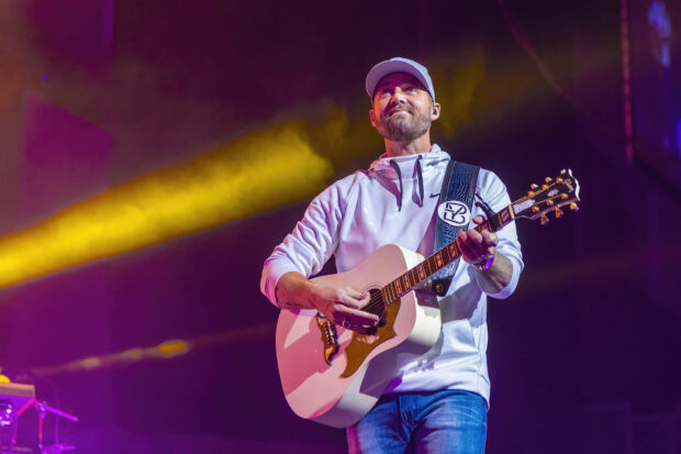 Brett Young performs with his guitar under colorful lights during a concert, HD Desktop Wallpaper