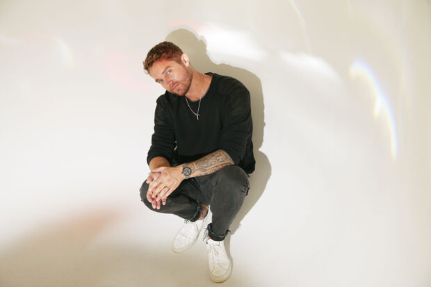 A man in casual black clothes poses with his hands together and tattoos on his arm, 2K Desktop Wallpaper