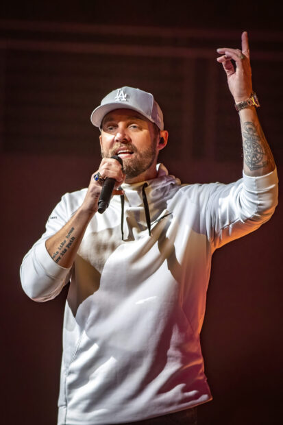 Brett Young is performing live with a microphone and expressive gesture, 2K Phone Wallpaper