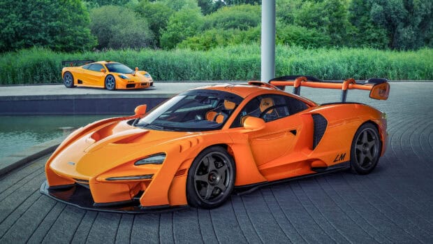 A bright orange McLaren Senna is parked near a green landscape with another car in the background, 4K Desktop Wallpaper