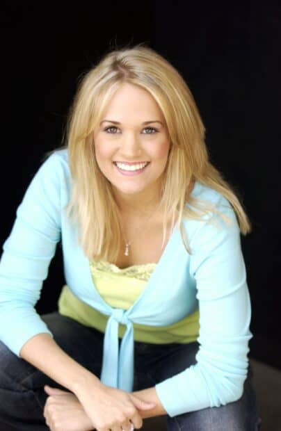 Carrie Underwood smiles warmly in a blue top against a dark background, 2K Mobile Wallpaper