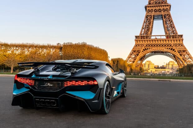A Bugatti Divo is parked near the Eiffel Tower with autumn trees in the background, 2K Desktop Wallpaper