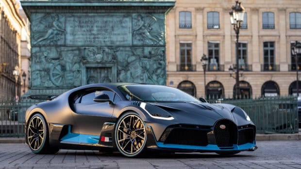 A Bugatti Divo sports car is parked on a street with historic buildings in the background, 4K Desktop Wallpaper