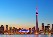 The CN Tower in Canada lights up the city skyline during dusk with colorful illumination, HD Desktop Wallpaper