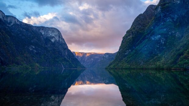 The Norwegian fjords showcase calm waters reflecting the mountains under a colorful sky, 2K Desktop Wallpaper