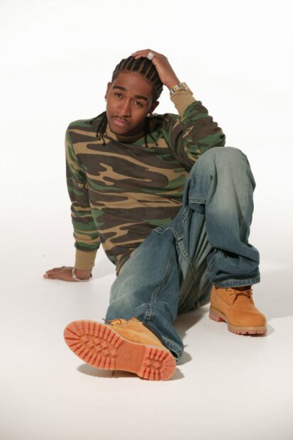Omarion is sitting on the floor wearing a camouflage sweater and denim jeans, HD Mobile Wallpaper