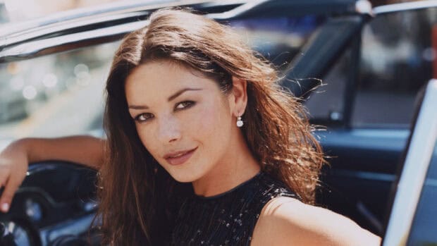 Catherine Zeta Jones wears earrings sitting in a car smiling softly, 2K Desktop Wallpaper