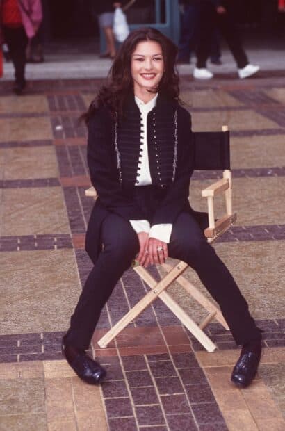 Catherine Zeta Jones sitting outdoors smiling in formal outfit, 2K Mobile Wallpaper