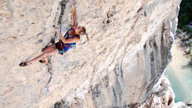 A woman is rock climbing on a steep cliff with safety gear, HD Desktop Wallpaper