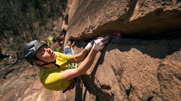 A climber in a yellow shirt grasping a rock face during a rock climbing activity, HD Desktop Wallpaper
