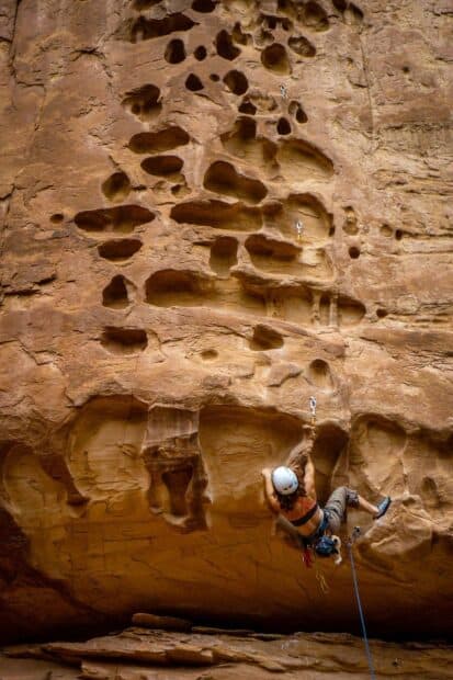 A climber with safety gear ascending a steep rock surface in rock climbing wallpapers, HD Mobile Wallpaper