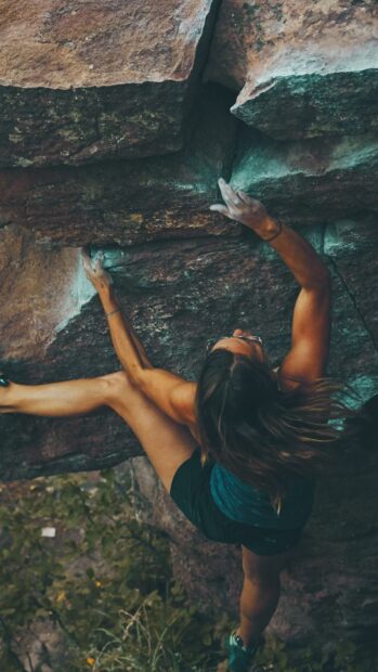 A person is engaged in rock climbing on a rugged cliffside showing strength and focus, HD Phone Wallpaper