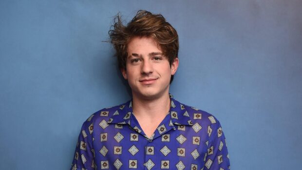 Charlie Puth wearing a blue patterned shirt against a plain blue background, 2K Desktop Wallpaper