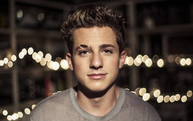 A close up portrait of Charlie Puth with blurred lights in the background, 2K Desktop Wallpaper