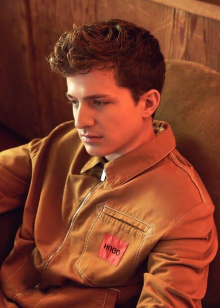Charlie Puth is sitting and looking down with a serious expression, HD Mobile Wallpaper