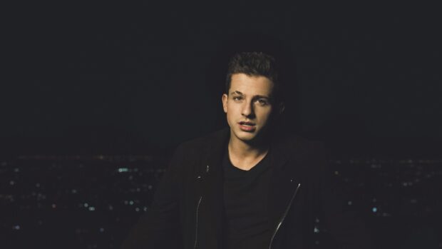 Charlie Puth is pictured wearing a black jacket against a dark cityscape at night, 4K Desktop Wallpaper