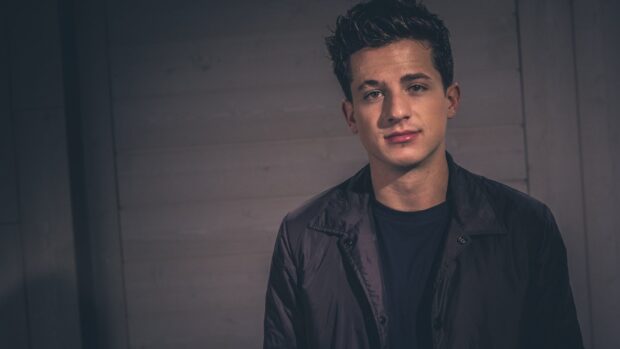 Charlie Puth Wallpapers showing a man wearing a dark jacket against a gray background, HD Desktop Wallpaper