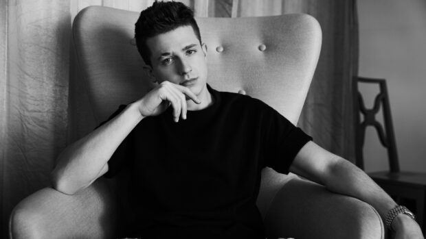 Charlie Puth sitting thoughtfully in a chair wearing a black shirt, 4K Desktop Wallpaper