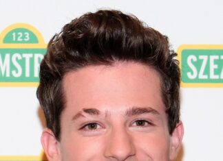Charlie Puth is smiling wearing a black jacket and white shirt at an event, 2K Mobile Wallpaper
