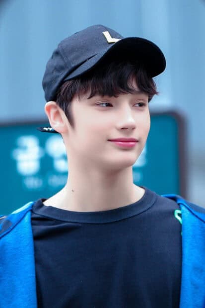 A close up of Huening Kai smiling while wearing a cap and casual clothes, HD Phone Wallpaper