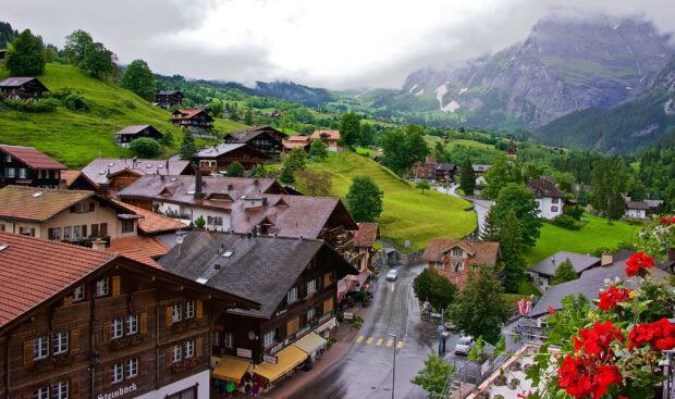 A charming village nestled in lush green hills with traditional houses and winding roads, 2K Desktop Wallpaper