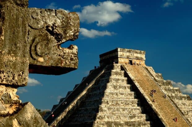 The Chichen Itza pyramid stands tall against a clear sky with a stone carving in the foreground, HD Desktop Wallpaper