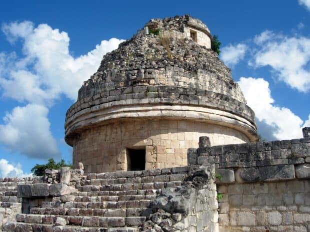 The Chichen Itza observatory tower stands tall against a blue sky with clouds, 2K Desktop Wallpaper