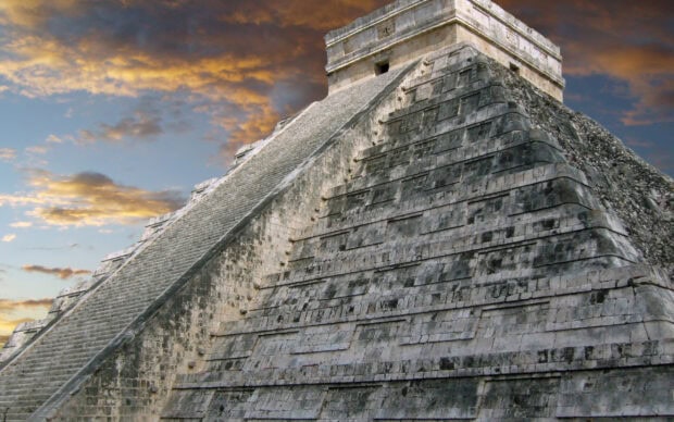 The Chichen Itza pyramid stands prominently under a cloudy sky at sunset, 2K Desktop Wallpaper