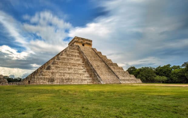 The Chichen Itza pyramid stands tall under a partly cloudy sky with green grass in front, HD Desktop Wallpaper