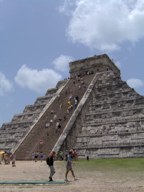 Visitors climbing the ancient Chichen Itza pyramid under a blue sky, HD Desktop Wallpaper